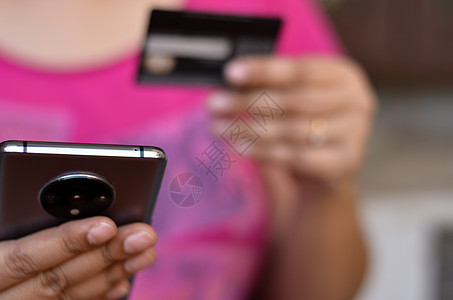 一位女士左手看着她的智能手机并用她的信用卡或借记卡进行数字支付的镜头 概念数字金融和金融科技 数字银行数据购物商业机动性交易电话图片