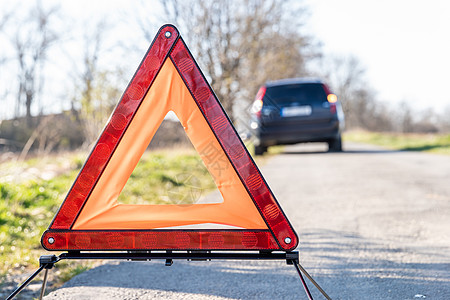 红色警示三角形 在一辆破车前面的路上图片