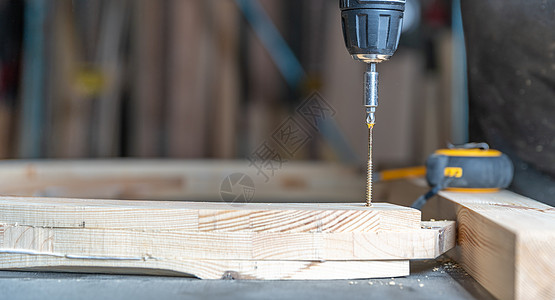 使用电钻比特在木制家具内用电钻头把木制家具硬件建筑工作工人机器力量男人木头钻孔电池图片
