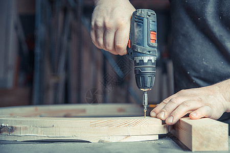 使用电钻比特在木制家具内用电钻头把木制家具建筑钻头建造螺栓工具木头安装钻孔乐器工作图片