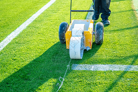 在比赛前使用特殊机器在草地上用白色油漆在足球场上画白线图片