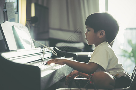 小男孩在家弹钢琴和音乐平板电脑房间音乐家孩子们女孩爱好旋律教育钢琴钢琴家练习图片