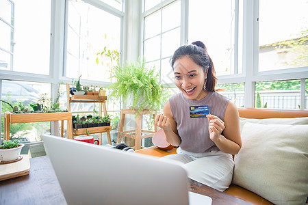 亚裔妇女拿着信用卡并且使用智能手机购物技术银行零售银行业电脑电子商务女士卡片顾客互联网图片