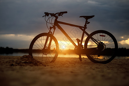沙滩上运动自行车的轮椅 日落女士耐力训练海滩速度太阳运输运动员铁人背包图片