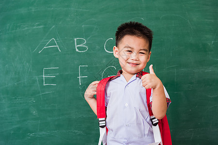 身着校服 有书包和Bob学生制服的幼童幼儿园手指男生课堂绿色学校手势微笑黑板学习快乐图片