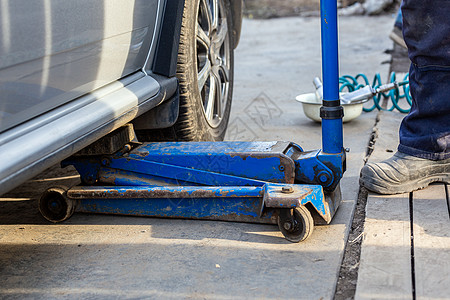 银色民用车在户外汽车车间用旧液压地板插件吊起 换轮胎程序图片