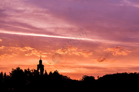 月光下金色的夕阳天空上 含柔软云彩的教堂和森林地平线图片