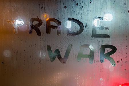 夜间湿窗玻璃上写的贸易战字样 背景模糊图片