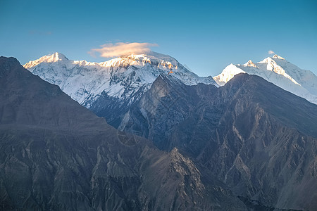 太阳升起在雪盖的山脉上 与蓝天相对图片