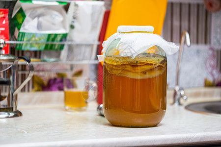 在厨房桌上的玻璃罐里装着自制的Kombucha茶玻璃食物活力文化果汁生活液体饮食奶奶气泡图片