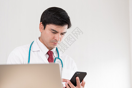 一名女医生必须在医院使用手机工作房间手术医师诊所药品男人卫生技术微笑桌子图片