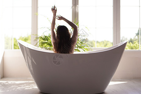一个有吸引力的女孩在洗澡时放松光背景 照片模糊了太阳身体泡沫肥皂女性卫生女士护理窗户化妆品图片