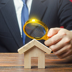 一个人正在通过放大镜研究一座房子 房地产的公允价值 物业估价 合法交易 施工标准和质量 购买协议的合法性和透明度图片
