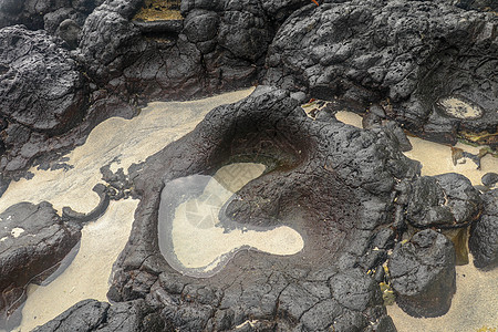 底部有白色沙子的岩石凹陷处充满了海水 在印度洋海岸巴厘岛印度尼西亚的熔岩床中挖掘出的小池塘 潮水在黑色岩石中挖出了小湖海岸火山冲图片