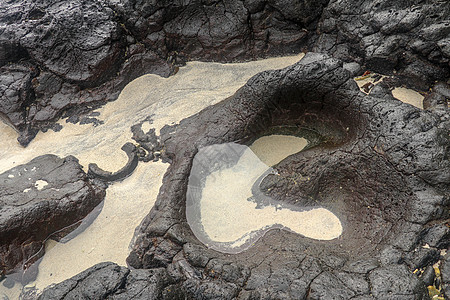 底部有白色沙子的岩石凹陷处充满了海水 在印度洋海岸巴厘岛印度尼西亚的熔岩床中挖掘出的小池塘 潮水在黑色岩石中挖出了小湖矿物海岸天图片