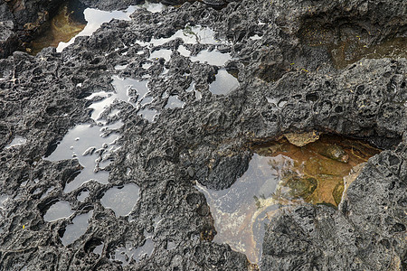 底部有白色沙子的岩石凹陷处充满了海水 在印度洋海岸巴厘岛印度尼西亚的熔岩床中挖掘出的小池塘 潮水在黑色岩石中挖出了小湖支撑孤独沿图片