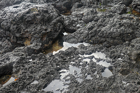 底部有白色沙子的岩石凹陷处充满了海水 在印度洋海岸巴厘岛印度尼西亚的熔岩床中挖掘出的小池塘 潮水在黑色岩石中挖出了小湖石头海岸线图片