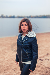 穿黑夹克的漂亮女孩 站在水边沙滩上图片