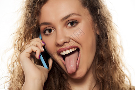 疯狂的年轻女孩在电话里说话 用舌头伸出舌头图片