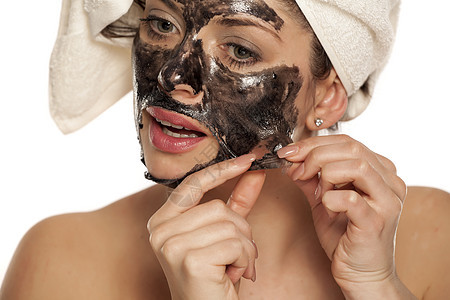 女人脱下她脸上的黑面罩化妆品程序美容毛巾护理黑色皮肤净化治疗温泉图片