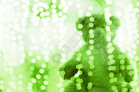 泰迪熊娃娃在灯光线散景绿色白色明亮的圣诞节或新年快乐在闪闪发光的绿色背景模糊散景明亮选择性焦点图片