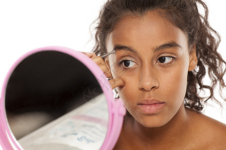 年轻美丽的黑人女子 拔眉毛黑色眼睛女性女孩工具皮肤镜子采摘治疗头发图片