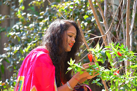 一个年轻美女的近身 看着红色的木须花朵图片