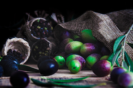 黑色 绿色和紫色橄榄在麻袋里 还有橄榄叶的死寂生命 黑食品技术和食物概念图片