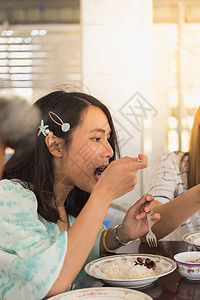 妇女在餐厅餐桌上吃着饭的食物桌子朋友木头享受房间女孩小吃早餐女性用餐图片
