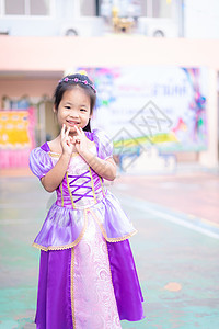 穿着公主服装站着的可爱笑笑小女孩肖像童年微笑学校派对乐趣金子裙子快乐教育角色图片