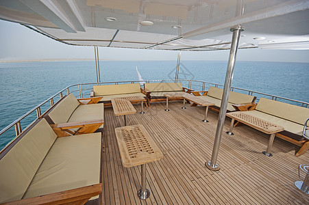 豪华汽车游艇甲板上的桌椅家具柚木桌子热带蓝色巡航栏杆海景地平线沙发图片
