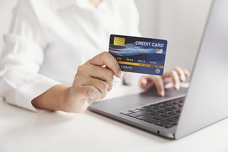 持有信用卡和使用笔记本电脑的手持信用卡设备技术组织基准互联网贷款钱包卡片屏幕账单图片