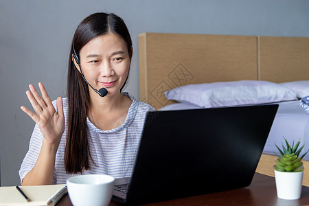 在家工作 新常态概念 有魅力的快乐女人戴着耳机通过笔记本电脑与同事进行视频会议 COVID-19冠状病毒大流行后的新常态图片