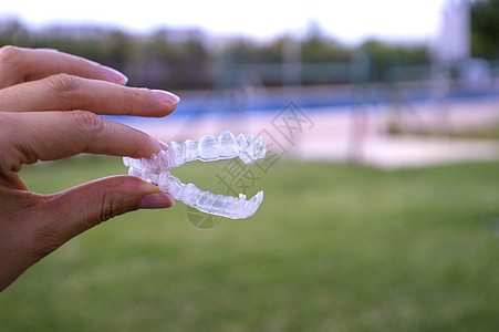 拿着透明牙齿矫正术的妇女手药品矫正固定器保留者牙医塑料对准器医疗女士隐适图片