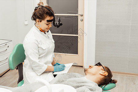 工作场所的年轻女牙医医生进行了一项患者调查 历史记录 医生的医疗保健工作场所设备 牙科女性工具假牙镜子口服牙疼卫生外科病人牙齿图片