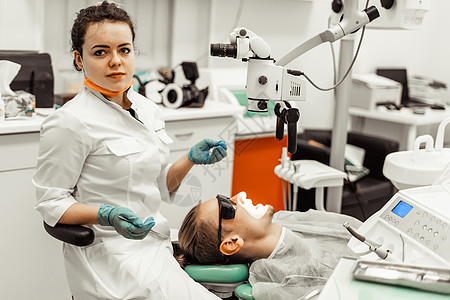 牙医年轻女人对待病人的男人 医生使用一次性手套 口罩和帽子 牙医在病人的嘴里工作 使用专业工具访问牙科医学诊所程序牙齿治疗口腔科图片
