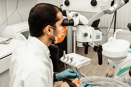 一位年轻的男牙医在治疗病人 牙科 外科的医疗操作 牙医的专业制服和设备 医疗保健装备医生工作场所 牙科工具医院微笑女士假牙牙科技图片