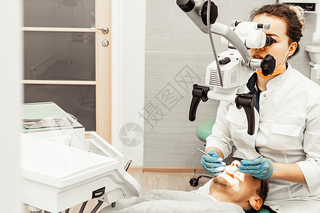 牙医年轻女人对待病人的男人 医生使用一次性手套 口罩和帽子 牙医在病人的嘴里工作 使用专业工具矫正牙钻衰变外科治疗程序牙疼卫生员图片