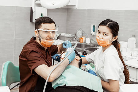 两个牙医治疗一个病人 牙医的专业制服和设备 医疗保健装备医生工作场所 牙科口腔科治愈口服牙齿衰变外科卫生诊所访问程序图片