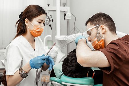 两个牙医治疗一个病人 牙医的专业制服和设备 医疗保健装备医生工作场所 牙科医学诊所访问卫生员工具女性矫正牙科技师医院牙钻图片