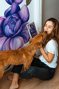 艺术家 设计师 宠物 年轻的女艺术家在室内的墙上作画 和狗一起工作和玩耍 宠物疗法 室内设计 创作过程职业画笔调色板刷子快乐乐趣图片