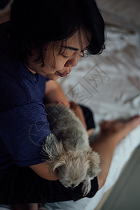 亚洲女人在卧室的床上抱着可爱的小狗床罩闲暇动物犬类友谊安慰注意力拥抱阳光考勤图片