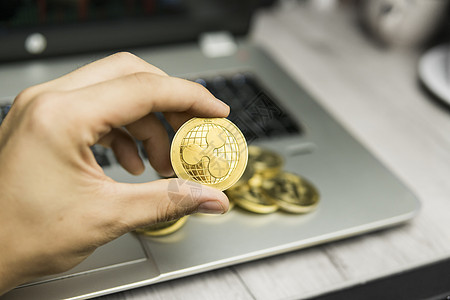 男性商务人士手持Ripple硬币 背景是笔记本电脑键盘和一堆金质硬币 虚拟货币和金融增长概念 Ripple贸易采矿日程商务波纹密图片
