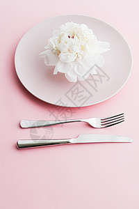 餐盘和餐具 配有小鲜花作为婚礼装饰品 放在粉红色背景 活动装饰最上桌菜以及甜点菜单厨师牡丹环境奢华晚餐假期推广风格生日花束图片