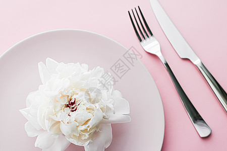 餐盘和餐具 配有小鲜花作为婚礼装饰品 放在粉红色背景 活动装饰最上桌菜以及甜点菜单环境牡丹厨师广告品牌用餐邀请函礼物生日花朵图片