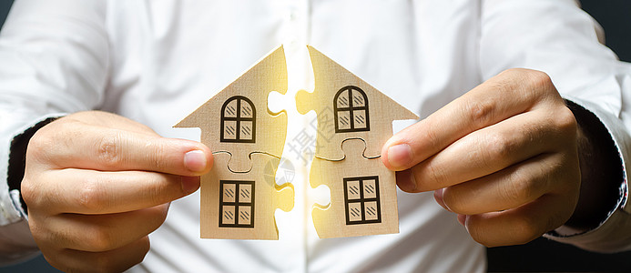 一个人将两个谜题连接成一整栋房子 上面写着 Mortgage 字样 建造自己的住宅楼 信用贷款买房 改善生活条件图片