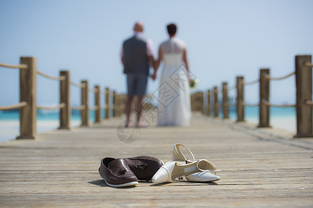 一对夫妇在木制码头上结婚 鞋子在前方女性海洋男性热带扶手新娘女士婚姻栏杆凉鞋图片