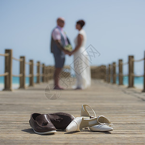 一对夫妇在木制码头上结婚 鞋子在前方女士海洋女性地平线木头扶手男人男性婚鞋婚姻图片