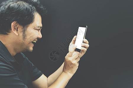 亚洲男人在深色风格中使用智能手机微笑马球旅行技术快乐电话衬衫情感头发黑色乐趣图片