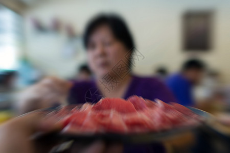 亚洲女人做饭 把肉牛肉放进热锅里图片